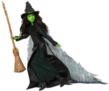 Witch figurine with green face and black outfit holding a broom on a white background